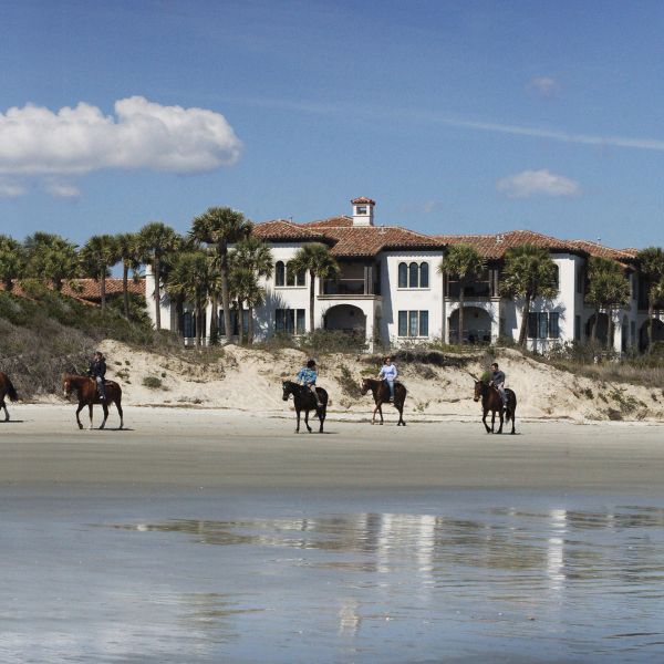 Guests ride horses on the beach at Sea Island Golf Club